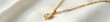 © Sourithideth - Elegant gold necklace lying on white velvet surface, refined, accessory