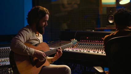 Poster - Musician and sound engineer recording guitar tunes in control room at professional music production studio. Artist playing electro acoustic instrument, live performance in soundproof space. Camera B.