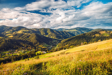 Poster - A splendid rustic scene with green rolling hills and distant huts illuminated by sunlight. Carpathian mountains, Ukraine, Europe.
