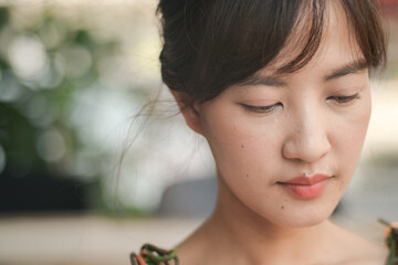 Poster - close up of thoughtful Asian young woman with natural makeup, soft lighting, and blurred background, creating serene and introspective mood