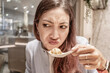 © EdNurg - Young woman making a disgusted face while holding a spoon with a dumpling in a chinese restaurant
