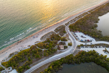 Wall Mural - Parking lot for tourists cars in front of ocean beach with soft white sand in Florida. Popular vacation spot at sunset