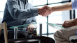 © Katsiaryna - Document discussion and handshake at the coffee table