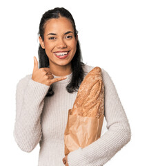 Wall Mural - Young Filipina holding artisan bread showing a mobile phone call gesture with fingers.