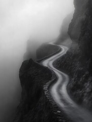 Poster - A winding road cuts through a foggy landscape, surrounded by rocky cliffs, creating a mysterious and atmospheric scene.