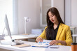 © Wasana - A woman is sitting at a desk with a yellow jacket on