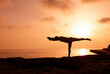 © RooM The Agency - Silhouette of a man doing a Warrior 3 yoga pose by the sea at sunset, Malta