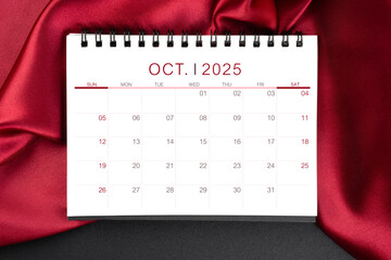 Wall Mural - October 2025 Monthly desk calendar with red silk on black leather background.