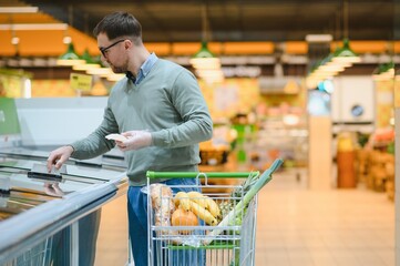 Sticker - Young man buying groceries at the supermarket. Consumerism concept