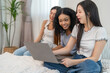 © Art_Photo - Diverse group of women friends smiling and talking while using laptop, browsing social media, shopping online, watching movies or series enjoying entertainment and connection digital lifestyle at home