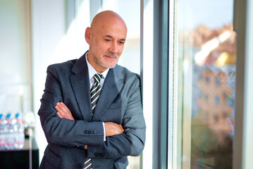 Wall Mural - Mid aged businessman standin by the window in a modern office