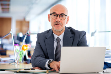 Wall Mural - Caucasian businessman sitting at desk and using laptop for work