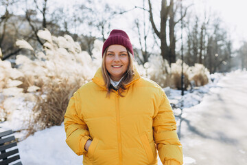 Happy 30s woman standing and looking happy outdoors. Urban lifestyle concept. Winter time. Beautiful woman walking on the modern city public park.