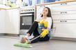 © KMPZZZ - Tired from clean, asian young woman after cleaning house sit alone on floor in kitchen room, hand holding mop after remove dust in apartment with stress and burnout housekeeping. Housewife do chores.