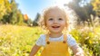 © milenialdesastudio - Happy toddler with curly blond hair laughing outdoors in a sunny autumn field.
