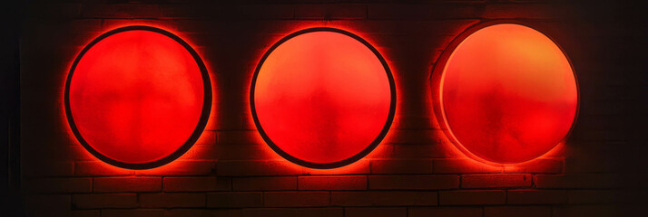 Poster - Round red glows illuminate a wall with distinct circular designs in varying brightness levels