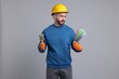 © New Africa - Man wearing hardhat with paintbrush and color selection chart on light grey background