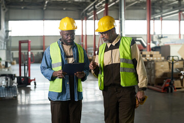 Aufkleber - Two intercultural workers of modern factory or plant looking at document in folder held by one of them during discussion