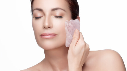 Wall Mural - Woman using rose quartz gua sha for facial massage