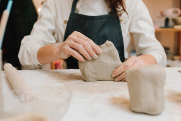 Fototapete - Potter is sculpting wet clay for ceramics products. Hands of a female potter making ceramic clay product on the table in the pottery workshop.