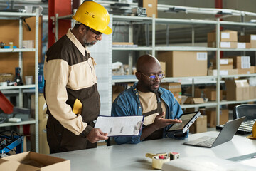 Aufkleber - Young male worker pointing at lamp while sitting by workplace and explaining his boss principles of equipment work