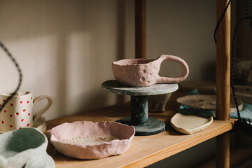 Poster - Shelf with handmade clay cups and plates in the pottery studio. Creating ceramics ware with own hands.
