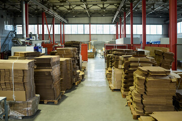 Aufkleber - Long aisle between two rows of stacked cardboard sheets on wooden pallets standing in modern factory warehouse