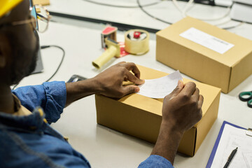 Aufkleber - Hands of young male worker of warehouse putting sticker with barcode on top of packed box with newly produced equipment
