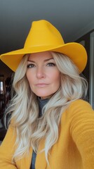 Wall Mural - Young woman with blonde wavy hair and yellow cap poses for a stylish portrait indoors