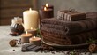 © Liana - Stacked brown towels with lit candles, chocolate pieces, and spices on a rustic wooden tray. A warm and cozy spa ambiance perfect for relaxation, self-care, and wellness concepts.