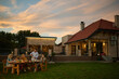 © Zamrznuti tonovi - Family enjoying dinner together in backyard as sun sets behind house