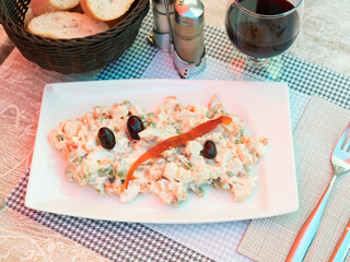 Wall Mural - Traditional salad of Spanish cuisine called Ensalada rusa, made from boiled potatoes, carrots, eggs, tuna, seasoned with ..mayonnaise and decorated with olives and a piece of fish on top