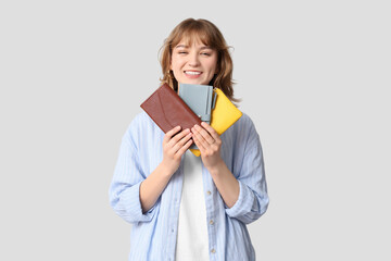 Wall Mural - Beautiful young woman holding wallets on grey background