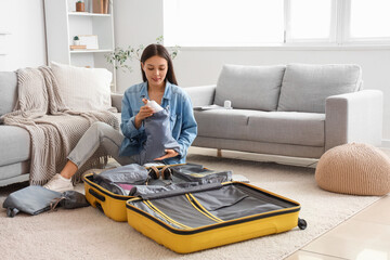 Wall Mural - Female Asian traveler putting water bottle into organizer at home