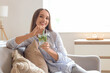 © Pixel-Shot - Beautiful young happy woman with glass of mojito sitting on sofa at home
