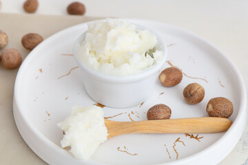 Poster - Plate with shea butter and nuts on light background, closeup