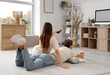 © Pixel-Shot - Young couple watching TV on carpet at home, back view