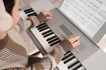 Wall Mural - Young woman playing synthesizer at home, closeup