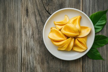 Wall Mural - Freshly peeled ripe jackfruit on a white plate with a leaf set against a wooden backdrop