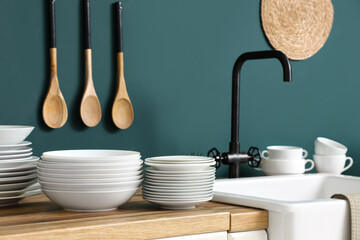 Wall Mural - Sink and wooden table with different plates near blue wall in kitchen