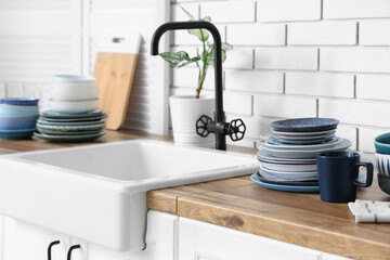 Wall Mural - Different plates and sink on wooden table near white brick wall in kitchen