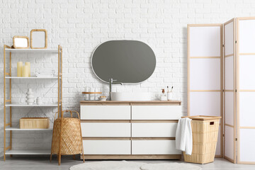 Wall Mural - Chest of drawers, shelving unit and folding screen near white brick wall in interior of bathroom