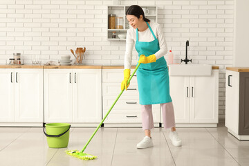 Wall Mural - Young woman washing floor with mop in kitchen