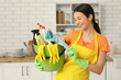 © Pixel-Shot - Young woman with bucket full of cleaning supplies in kitchen