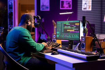 Aufkleber - Skilled male composer producing new songs on his mixing console, operating on professional gear in home studio. Artist audio engineer twisting knobs to adjust sound levels on tracks.