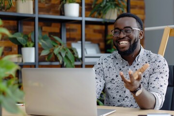 Aufkleber - Young entrepreneur is happily video conferencing on his laptop in his contemporary green workspace