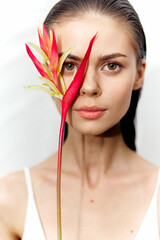 Poster - Beautiful young woman holding a vibrant red heliconia flower, showcasing natural beauty and elegance in a minimalistic setting.