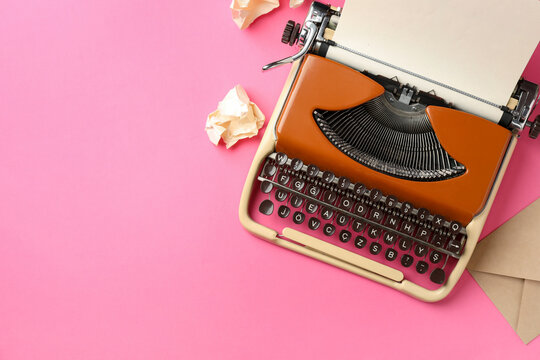 Vintage typewriter, crumpled paper and envelope on pink background, flat lay. Space for text