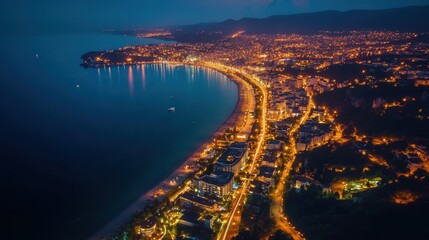 Poster - lively coastal city from above, captured at night, where the lights from the city shine brightly against the black sea