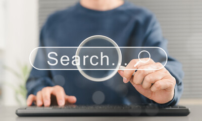 Wall Mural - SEO search engine optimization concept. Person uses keyboard while holding magnifying glass with search bar labeled 